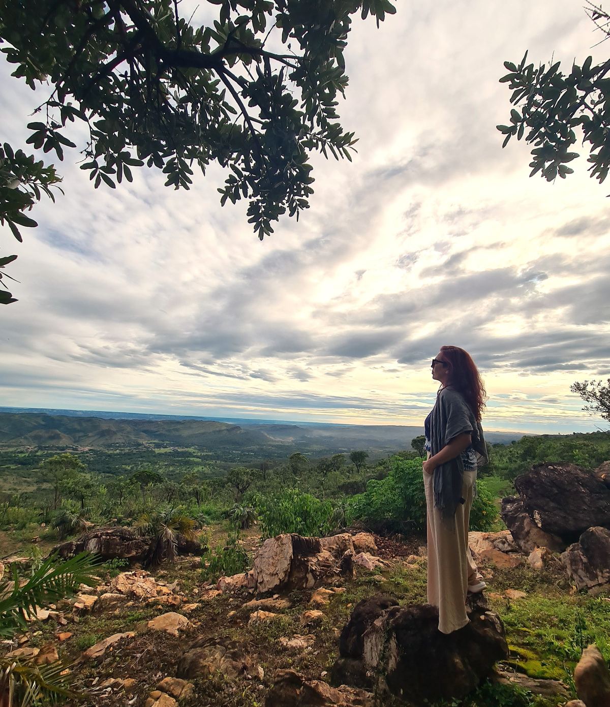 Adri observando o horizonte em uma trilha, em um momento de pausa e reflexão.